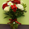 Bouquet of red and white flowers in a glass vase with a red ribbon