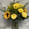 Yellow roses and sunflowers in a clear glass vase