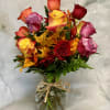 Mixed roses in a glass vase with autumn leaves
