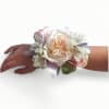 Pastel wrist corsage with peach rose, white alstroemeria, and ribbon on a person's wrist