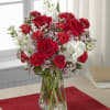 Red roses and white flowers arranged in a clear glass vase