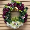 Floral wreath with purple roses and white flowers on a wooden wall