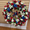 Large red, white, and blue floral wreath on a stand with ribbon