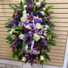 Standing floral spray with purple and white flowers on a metal easel