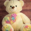 Cream teddy bear with colorful floral-patterned paws and chest