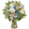 White roses and blue flowers arranged in a clear glass vase