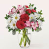 Bouquet of red roses, white daisies, and pink alstroemeria in a clear glass vase