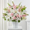 Pink roses and white lilies arranged in a white vase