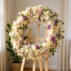 Large floral wreath of cream, blush, and purple flowers on a wooden easel