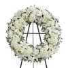 White funeral wreath with lilies, roses, and chrysanthemums on a stand