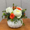 White and orange roses arranged in a white pumpkin vase