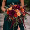 Woman holding a large bouquet of roses and dahlias in burgundy and peach tones