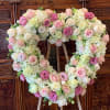 Heart-shaped floral arrangement with pink and white roses on an easel