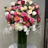 Large bouquet of pink, white, and peach flowers in a tall green vase