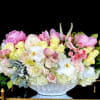 Large pastel floral arrangement in a white pedestal vase