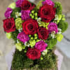 Heart-shaped bouquet of red roses, pink carnations, and green accents