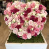 Heart-shaped arrangement of pink and white roses on a moss-covered base