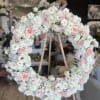 Large pastel floral wreath on a wooden easel with pink roses and white blooms