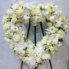 Heart-shaped white floral wreath on a stand