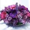 Purple and pink floral arrangement in a low black container