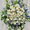 Large standing floral spray with white roses and blue flowers on an easel