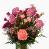 Pink roses and carnations arranged in a clear glass vase