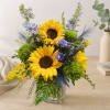 Bouquet of sunflowers and purple flowers in a clear glass vase