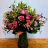 Pink roses and lilies arranged in a green glass vase