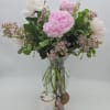Pink and white flowers in a glass vase with a candle in front
