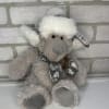 Plush gray teddy bear wearing a white hat and scarf