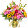 Bright mixed bouquet in a glass vase with a gold ribbon