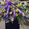 Large purple and yellow floral spray with ribbon on a stand