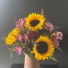Sunflowers and pink alstroemeria arranged in a tan vase