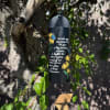 Black hanging wind chime with yellow flowers and white text