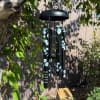 Black memorial wind chime hanging outdoors with blue leaf accents