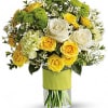 Yellow and white roses in a clear vase with green accents