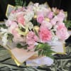Pink and white bouquet with roses, lilies, and carnations wrapped in gold-trimmed paper