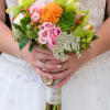 Bride holding a colorful bouquet with pink roses and orange blooms