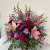 Pink lilies and roses arranged in a vase with tall purple spikes