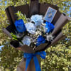 Blue roses and light blue carnations in dark wrap with a blue ribbon