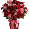 Red roses and pink carnations in a vase with a pink ribbon