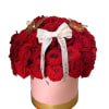 Red rose arrangement in a pink round box with a white ribbon