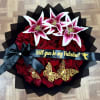 Bouquet of red roses topped with pink-and-white lilies and a black ribbon