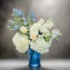 White and blue floral arrangement in a blue glass vase