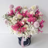 Pink and white mixed flower arrangement in a black hat box with a ribbon