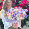 Woman holding a pastel bouquet in a pink hatbox