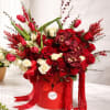 Red and white rose arrangement with tulips in a red hatbox