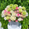 Round bouquet of pink, white, and green flowers in a white vase