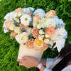 Handheld bouquet of cream, peach, and white flowers in a white wrap