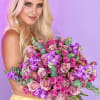 Woman holding a large bouquet of pink and purple roses with eucalyptus